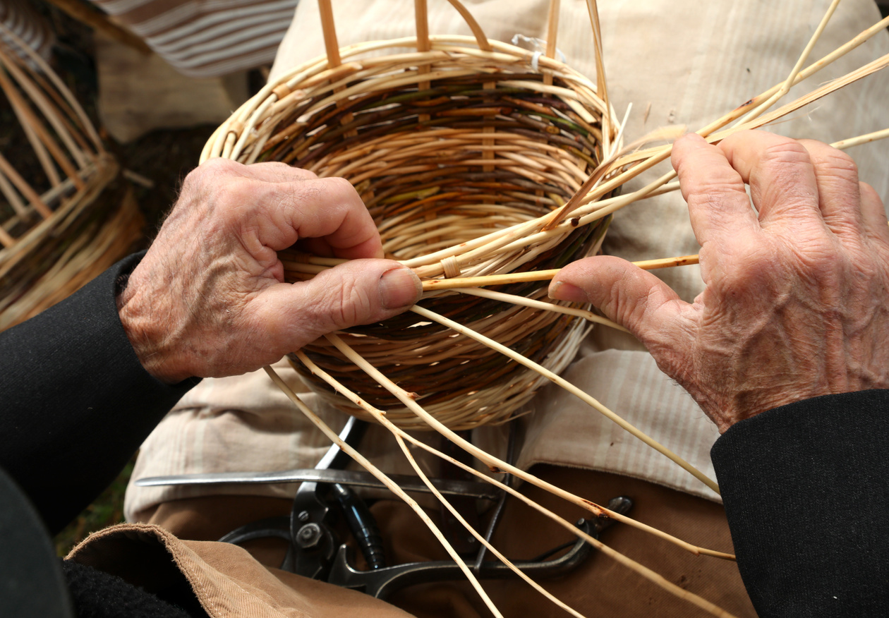 senior craftsmen with hands with arthrosis while weaving wicker